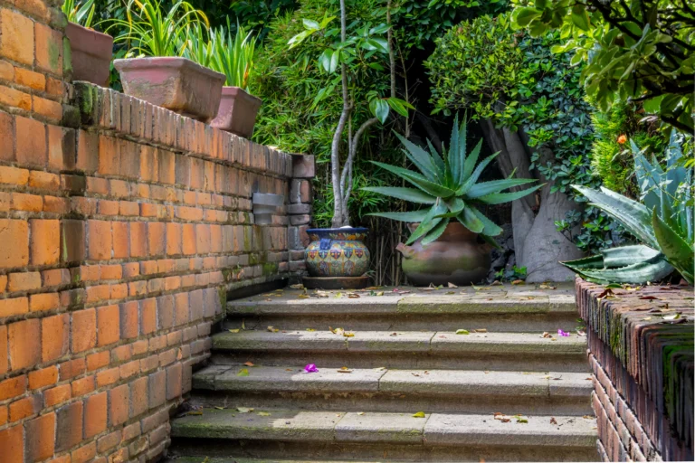 Brick patio steps with stone planters and greenery