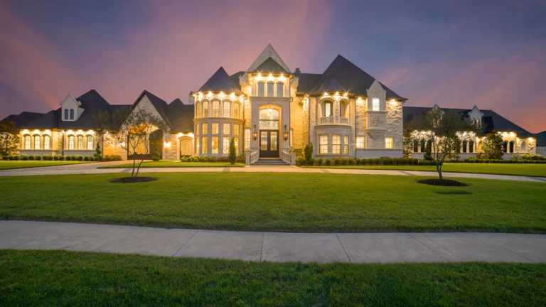 Large luxury home exterior at dusk with landscaped lawn