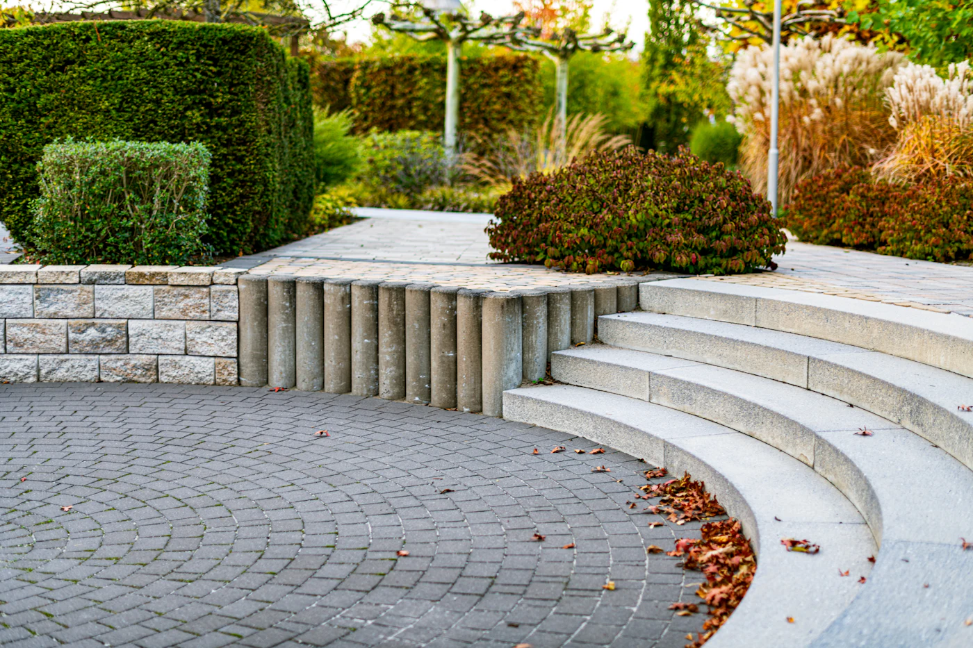 Paver patio with wide curved stone steps and planting beds