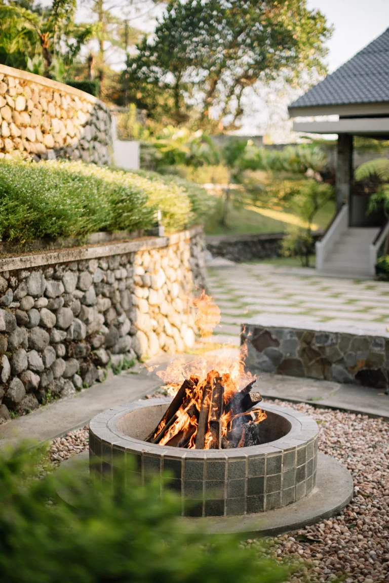 Stone fire pit beside a fieldstone retaining wall and paver patio