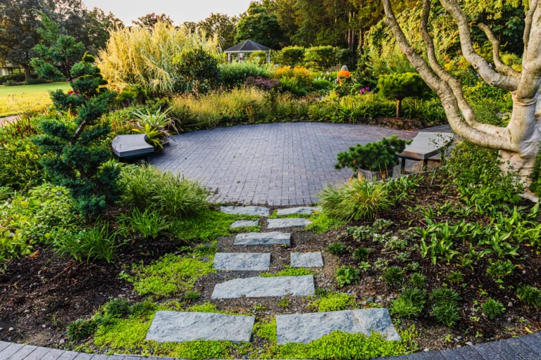 Stone path leading to a circular brick paver patio in a lush garden