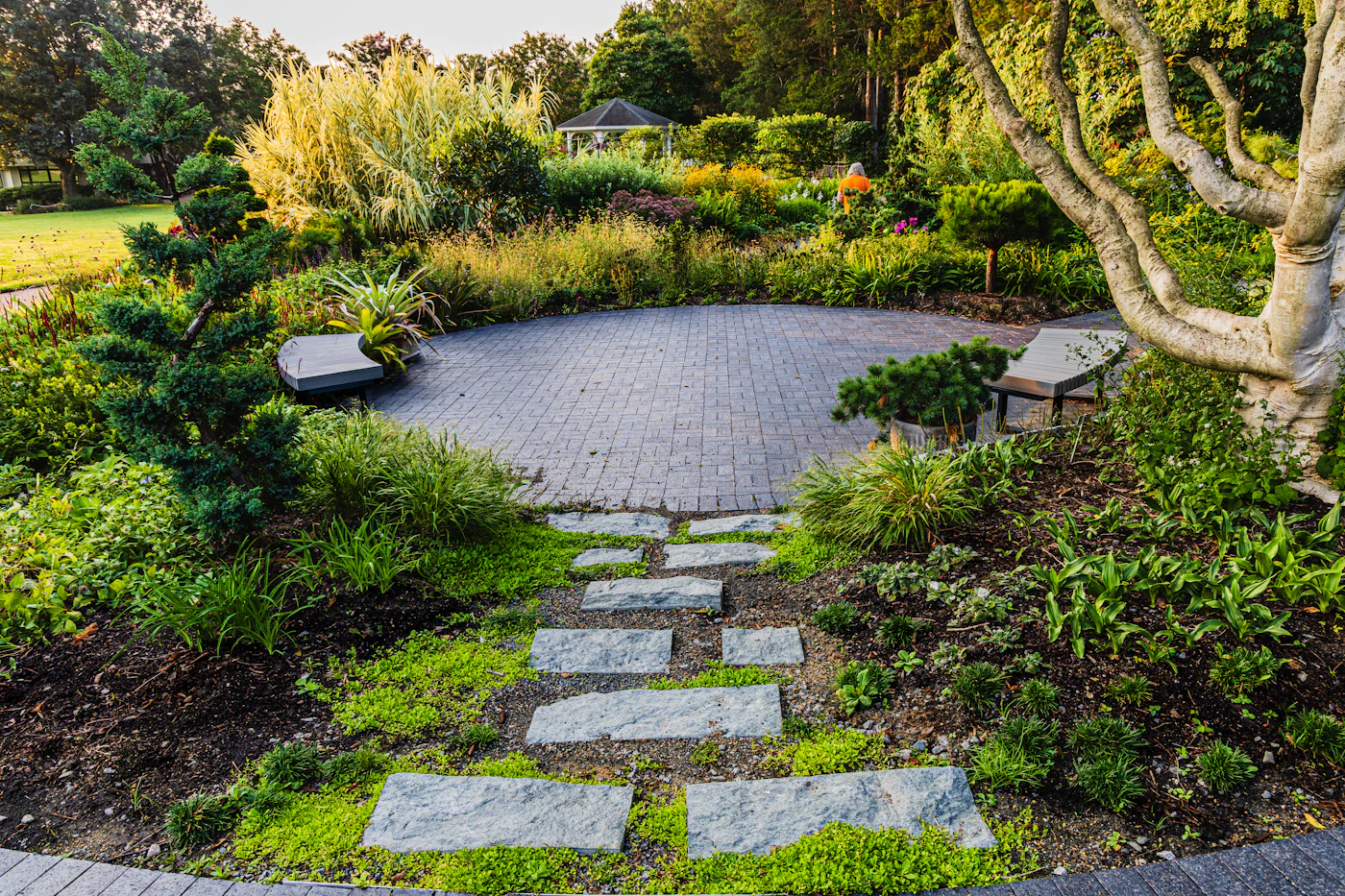 Stone path leading to a circular brick paver patio in a lush garden